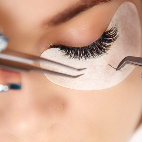 Eyelash Extension Procedure. Woman Eye with Long Eyelashes. Close up, selective focus.